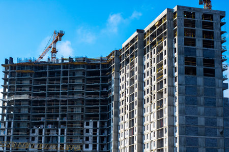 A dynamic construction site featuring multiple cranes and a significant highrise building that is...
