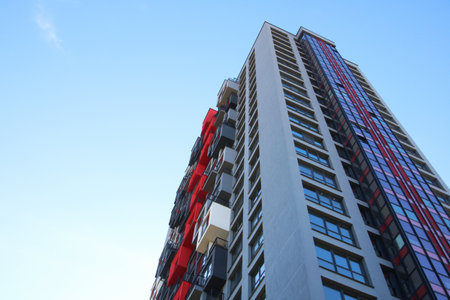While gazing upwards, I admire a remarkable tall building, set against the backdrop of a vivid blue...