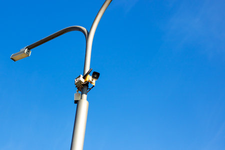 A street light stands tall against a vibrant blue sky, while the sun shines down on the...