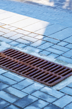 Two drains are positioned closely on a brick sidewalkの写真素材