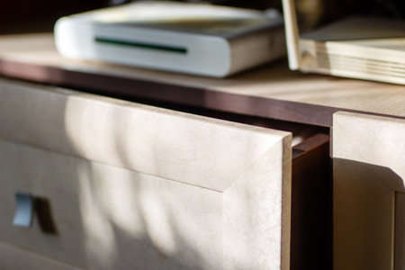 A beautifully crafted book rests on a sturdy table that is conveniently located beside a wellmade drawer, showcasing exquisite woodworkの写真素材