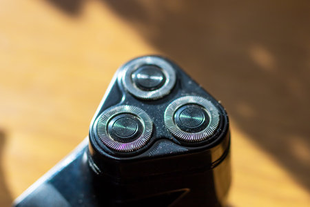 This image features a detailed closeup of a sleek shaver that showcases its three advanced blades,...