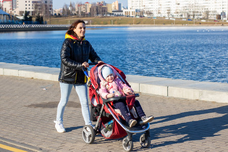 Belarus, Minsk - 25.03.2025: A woman is actively pushing a stroller that contains a baby inside itのeditorial素材