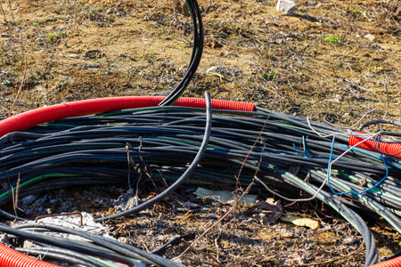 A close-up of coiled cables and wires resting on the ground, showing their rugged texture and color.