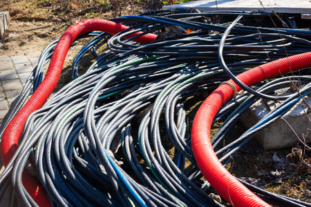 A chaotic mix of red and black cables tangled on the ground, showcasing industrial wiring...