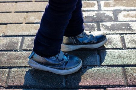 A person is currently wearing a stylish pair of blue shoes while standing on a textured brick...