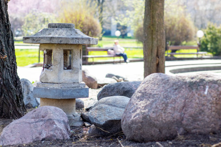 In a lovely park, a stone lantern is carefully placed atop a pile of rocksの写真素材