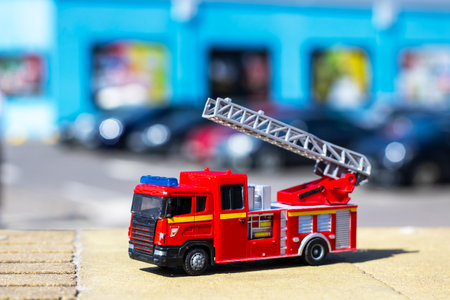 A colorful toy fire truck with a ladder is on a wooden table