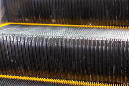 This image features a detailed closeup shot of the bottom area of an escalator, highlighting the...