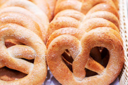 A delightful assortment of pretzels arranged in a basket, generously coated with sweet sugar on top,...