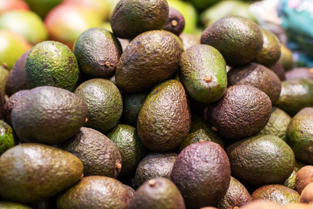 A delightful pile of ripe avocados stacked on top of each other gracefully resting on a wooden...
