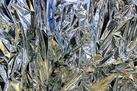 This image features a closeup shot showcasing a pile of crumpled aluminum foil with its shiny silver...