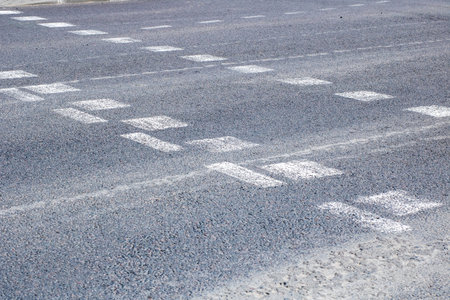 A detailed and closeup view of a road surface that has numerous footprints imprinted on it, possibly...