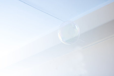 A beautiful soap bubble is gently floating in the air against a vibrant blue sky, creating a...