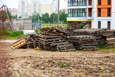 There is a stacked arrangement of wooden pallets located in a dirt field that lies in front of a...