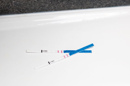 Two pregnancy test strips on a white surface, displaying the results of a home pregnancy test....
