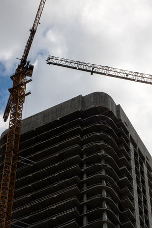 Dynamic construction scene with cranes towering over a high-rise building under development. Urban...