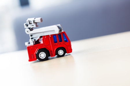 A vibrant red toy fire truck with a ladder sits on a wooden table, perfect for imaginative play and...