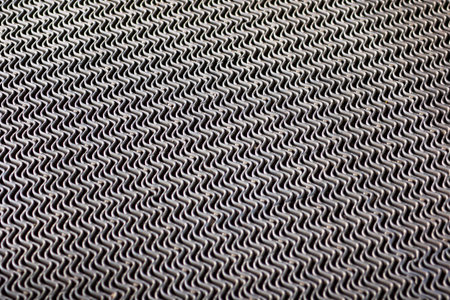 A close-up view of a textured metal mesh featuring an intricate wave pattern, ideal for industrial...