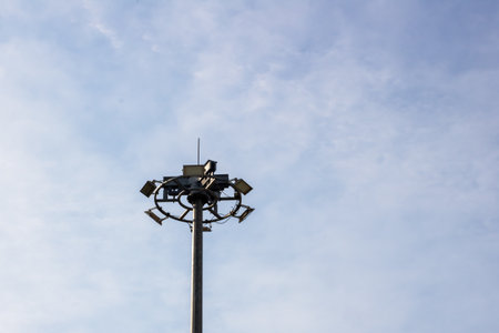 A tall surveillance light pole equipped with multiple cameras and lights, set against a clear blue...