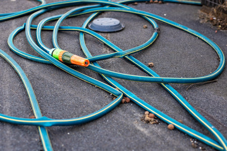 A variety of garden hoses are currently sprawled out on the ground, taking up space and creating a...