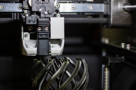 D printer nozzle printing metal lattice prototype, closeup of extruder depositing spiral filament...