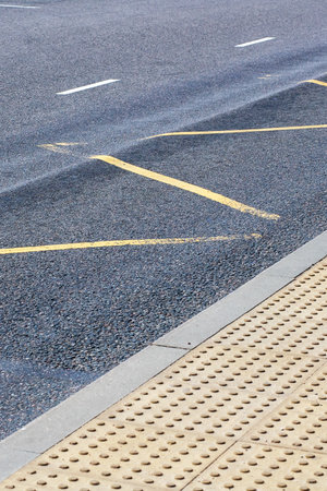 tactile paving asphalt platform edge showing highcontrast yellow studs, textured pavers, painted...