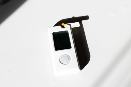 White digital device on textured surface bathed in bright studio light with deep angular shadow, visible screenの写真素材