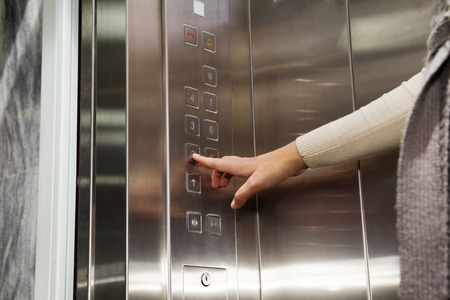 Elevator female hand clicks on the button  bronze  panel with numbers of floors