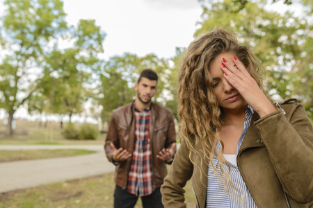 Attractive long haired woman feels disappointment while her boyfriend trying to explain relationship problemsの写真素材