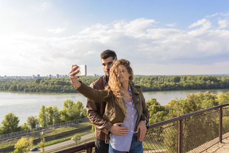 Modern couple taking a selfie photos close to river bankの写真素材