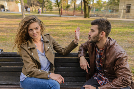 Young man and woman angry and conflicting on a park benchの写真素材