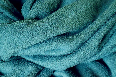 Close-up of blue, green, soft, warm, comfortable blanket, illuminated by early morning light, just...