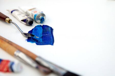 Blue stroke of oil paint on a white canvas with a palette knife and brushの写真素材