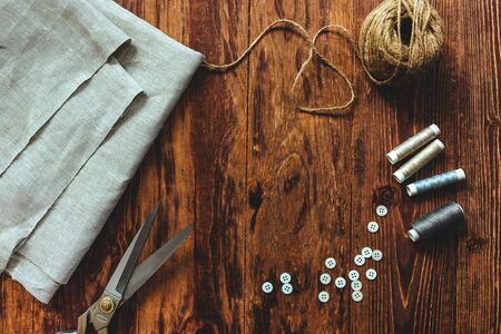 Sewing thread scissors buttons for seamstress on wooden background.の写真素材