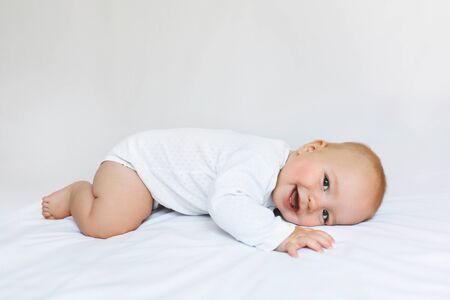 Beautiful baby on the white bad with clean sheet.