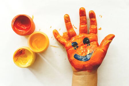 Drawing on a childs hand. Red yellow orange gouache.の写真素材
