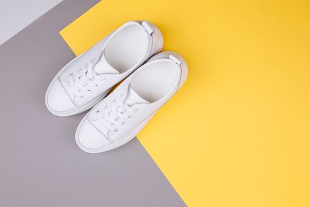 Fashion, sport, blog, blogging, lifestyle, well-being trendy concept. Pair of white female sneakers on yellow and grey background, top view, copy space, flat lay.の写真素材