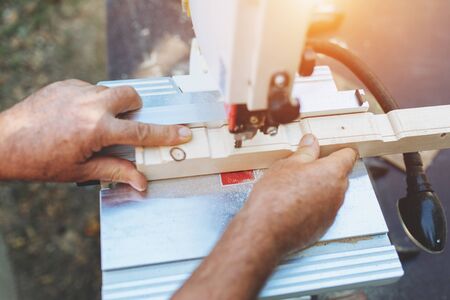 Carpenter uses a linear saw to cut wooden beams outdoors.の写真素材