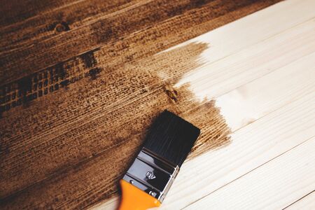 Man paints a wooden surface with dark paint.