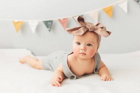 Portrait of a cute 3 months baby lying down on a blanket, bow on the head.