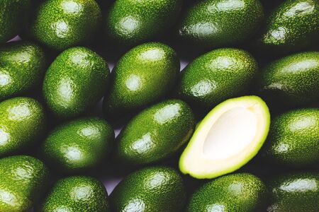 Many bright, delicious green avocados stacked on a supermarket shelf.の写真素材