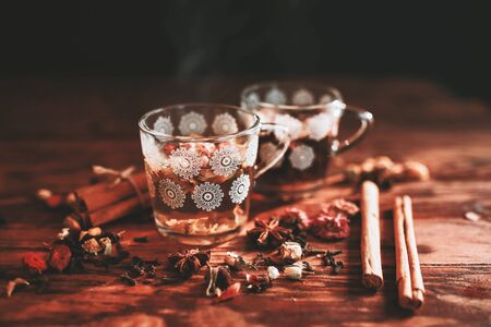 Two cups of herbal tea on a wooden table in the rays of the setting sun. Spices, cinnamon, dried rose, thyme, cloves. top view,の写真素材