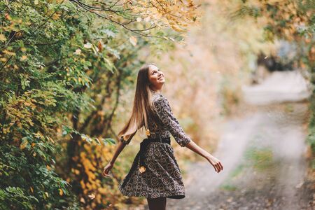 Beautiful elegant woman dancing in a park in autumnの写真素材