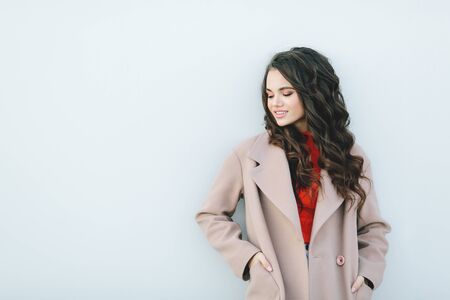 Hipster girl wearing orange t-shirt, jeans and coat posing against rough street wall, minimalist urban clothing style, mockup for tshirt print storeの写真素材