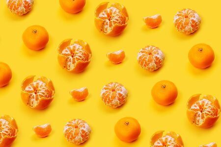 Mandarin pattern on a yellow or orange background, New Year and Christmas concept, peeled tangerines and peeled, mandarin slice. Flat layの写真素材