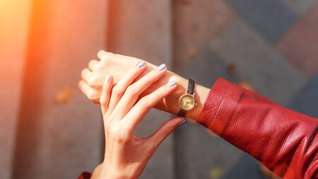 street style fashion details. close up, young fashion blogger wearing a jacket and a analog wrist watch. stylish woman checking the time on her watch. autumn fall season.の写真素材