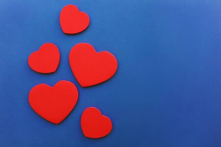 Many wooden red hearts on blue background, Valentine's Day concept, close-up. Place for textの写真素材