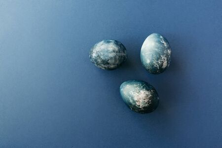 Frame with group gold and blue speckled easter eggs with copy space for text. On blue background. Happy Easter card.の写真素材