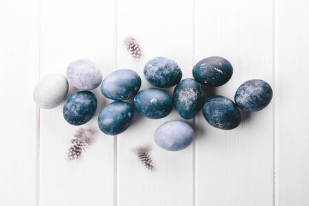 Beautiful group ombre blue Easter eggs with quail eggs and feathers on a white wooden background. Easter concept. Border eggs. Copy space for text. Classic blue color of year 2020の写真素材